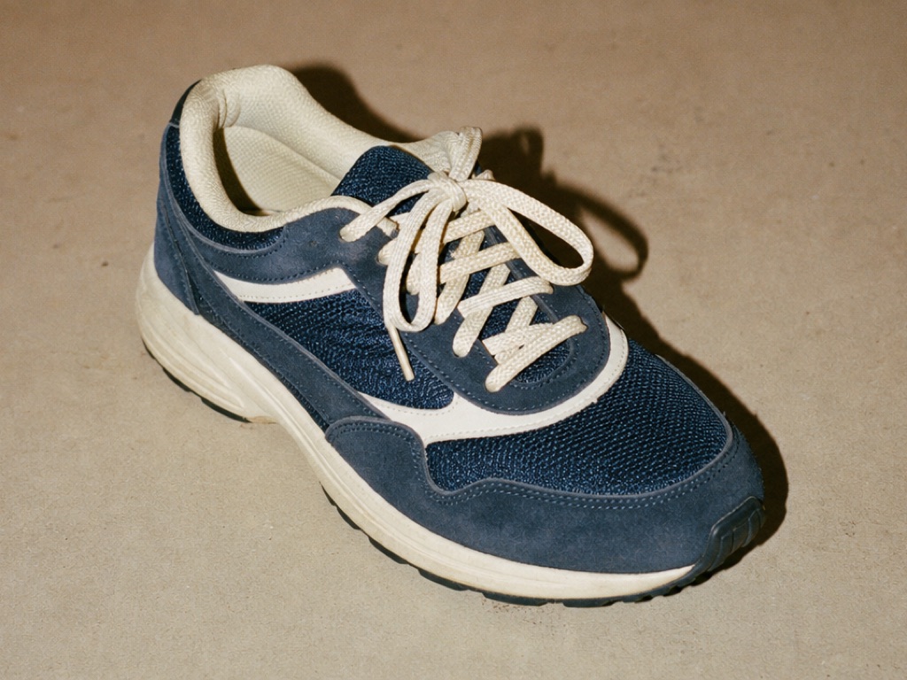 Navy and cream running shoe on a beige surface