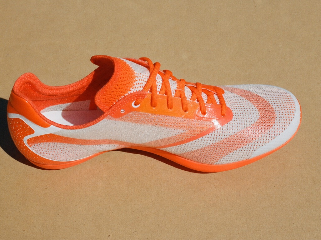 Neon orange racing shoe on a beige surface
