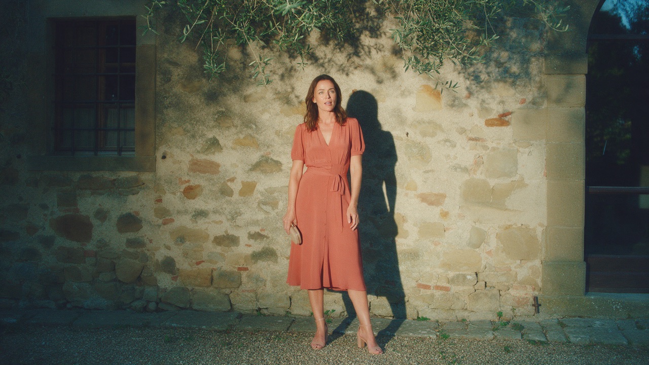 Woman in a terracotta midi dress with nude heels and a small clutch